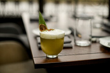 Cocktail decorating with a whipped cream, tropical leaf, dried orange and red pepper peas