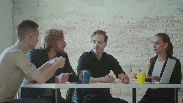 team of young professionals communicate at a table in the office