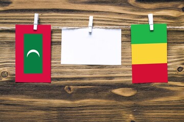 Hanging flags of Maldives and Mali attached to rope with clothes pins with copy space on white note...