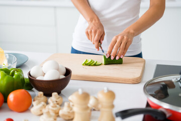 Close up cropped photo of joyful housewife prepare feast for her veggie family cutting green organic cucumber on chopping board in kitchen white house indoors