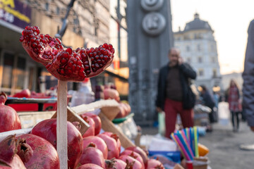 Street market stall with fresh juicy red pomegranate fruits in an autumn day. Sweet chopped pomegranate