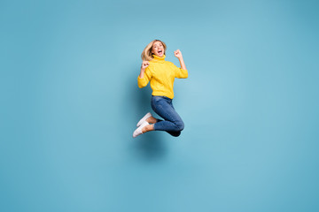 Fototapeta na wymiar Full length profile photo of crazy lady jumping high celebrating winning free trip abroad rejoicing wear knitted yellow pullover jeans isolated blue color background