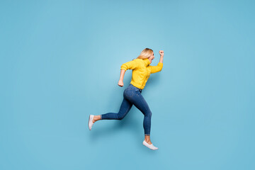 Fototapeta na wymiar Full length photo of amazing blond lady jumping high rushing discount low prices shopping wear knitted yellow pullover jeans isolated blue color background
