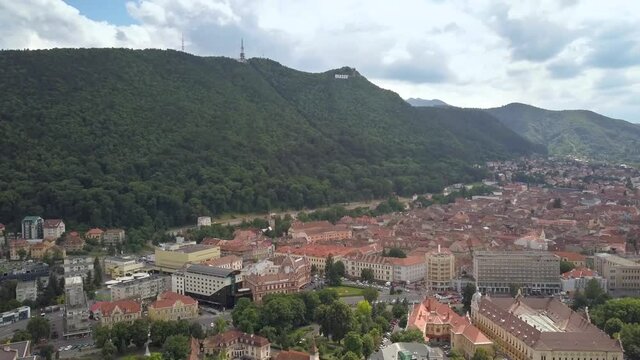 Aerial view of Brasov city, medieval town situated in Transylvania, Romania. Old architecture surrounded with big Carpathian mountains covered with dense green forest.