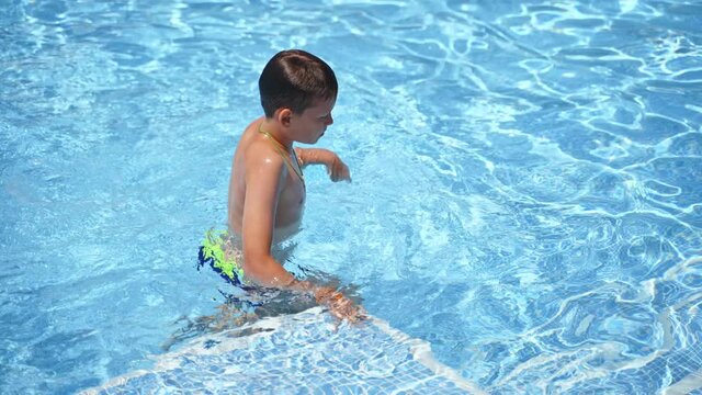 Happy child on summer vacation. Boy having fun in the swimming pool. Teenager going out of the pool.