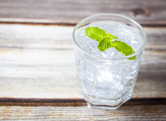 Glass of water ice cubes with mint on wooden table