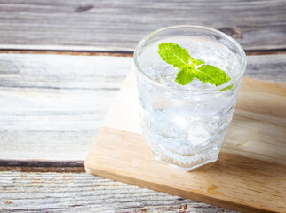Glass of water ice cubes with mint on wooden table