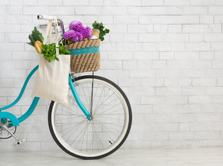 Fototapeta na wymiar Bicycle with wildflowers and organic food over white bricks wall