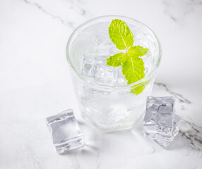 glass of water with ice and mint on white background