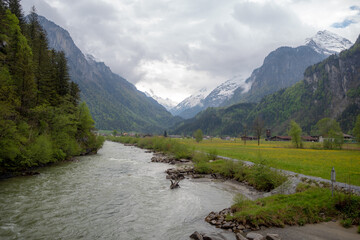 Naklejka na ściany i meble Beautiful scene of aare river and fresh meadow on cloudy sky and mountain background with copy space, Switzerland