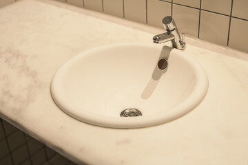 Simple white basin in wide circle shape in a marble table