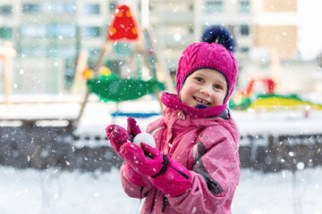 Cute adorable caucasian little girl winter portrait holding snowball in hands ready for snow fight...