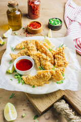 Breaded chicken strips with tomato sauces on a plate. Fast food on beige rustic background. Selective focus