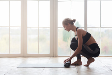 Woman after practicing yoga, rolling yoga mat at studio