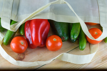 Reusable eco friendly bamboo grocery shopping bag with vegetables-red pepper, fresh tomatoes cucumber and avocado on green background. Less plastic.
