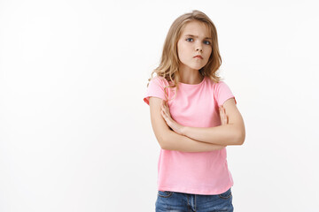 Serious-looking offended angry little cute blond girl, sulking frowning upset, cross arms chest...