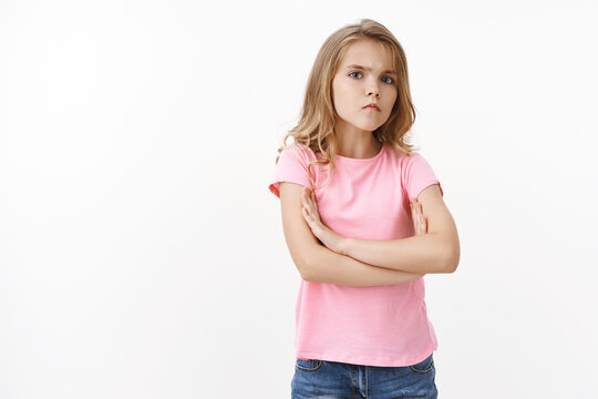 Serious-looking offended angry little cute blond girl, sulking frowning upset, cross arms chest block unsatisfied pose, boy insulted her waiting apology complaining displeased, stand white background