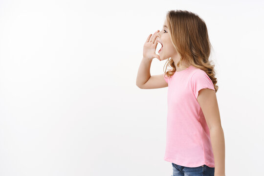 Profile Shot Cute Lovely Blond Young Girl, Child Calling Friend Hold Hand Near Opened Mouth Shouting Name, Searching Parent Smiling Joyfully, Playing Hide-n-seek On Playground, Stand White Background