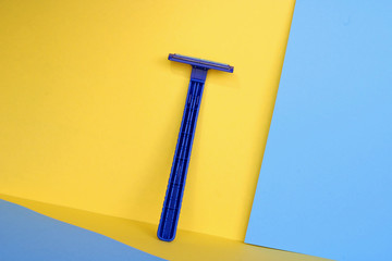 Blue shaving blade on yellow and blue background.