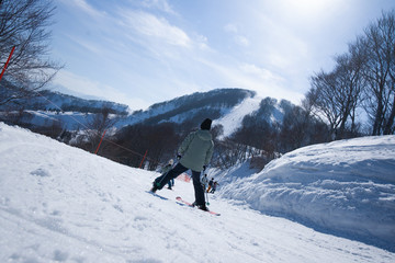 Fototapeta na wymiar Skier skiing downhill during sunny day in high mountains, Yuzawa Niigata Japan.