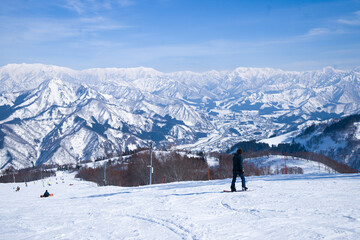 Fototapeta na wymiar Skier skiing downhill during sunny day in high mountains, Yuzawa Niigata Japan.