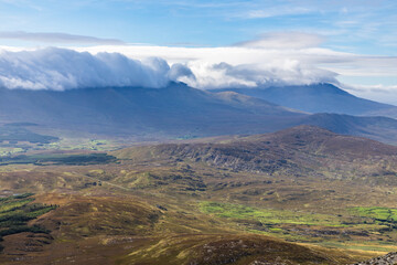 Fototapeta premium Clouds covering mountain and valley with fields and forest taken from Croagh Patrick mountain