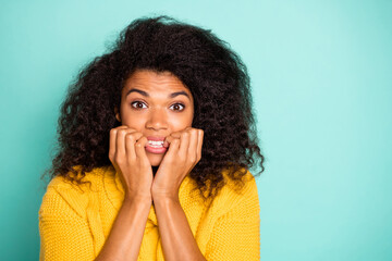 Closeup photo of funny dark skin lady holding fingers in mouth nervous about made mistake wear yellow knitted jumper isolated blue teal color background