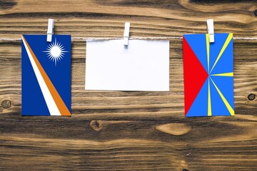 Hanging flags of Marshall Islands and Reunion attached to rope with clothes pins with copy space on...