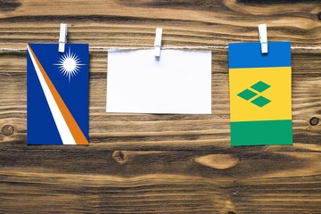 Hanging flags of Marshall Islands and Saint Vincent And The Grenadines attached to rope with...