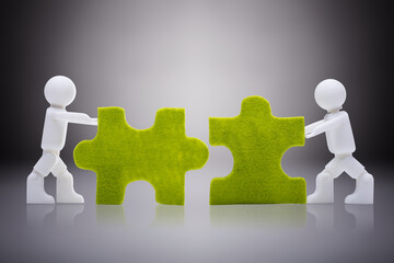 White Human Figures Joining The Green Jigsaw Pieces