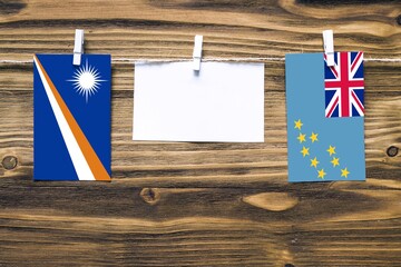 Hanging flags of Marshall Islands and Tuvalu attached to rope with clothes pins with copy space on...