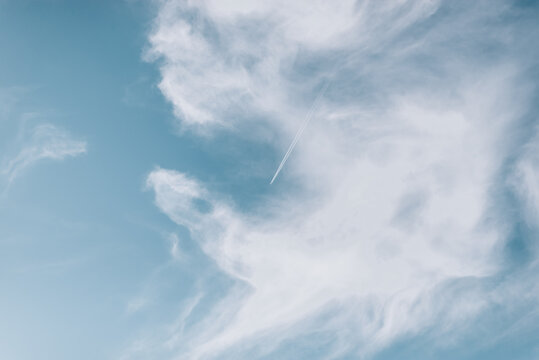 Beautiful picture of white plane flying with trail in blue sky