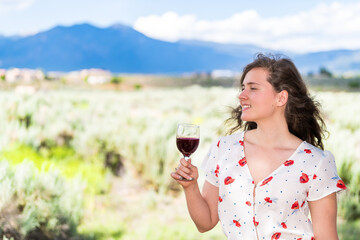 Woman tasting red wine by view of Taos Sangre de Cristo mountains from Ranchos de Taos valley...