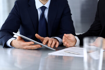 Business people using tablet computer while working together at the desk in modern office. Unknown businessman or male entrepreneur with colleague at workplace. Teamwork and partnership concept