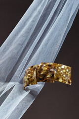 Object shot of a big automatic hairpin, lying on a dark brown background. The hairpin is decorating...