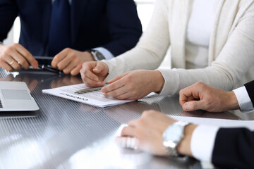 Business people discussing contract working together at meeting at the glass desk in modern office. Unknown businessman and woman with colleagues or lawyers at negotiation. Teamwork and partnership