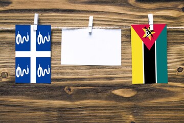 Hanging flags of Martinique and Mozambique attached to rope with clothes pins with copy space on...