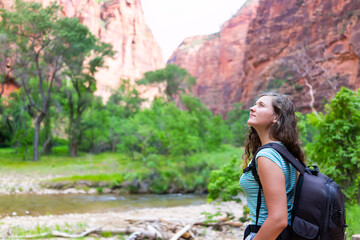 Narrows riverside trail walk in Zion National Park with young woman girl exploring hike by river on summer day with backpack