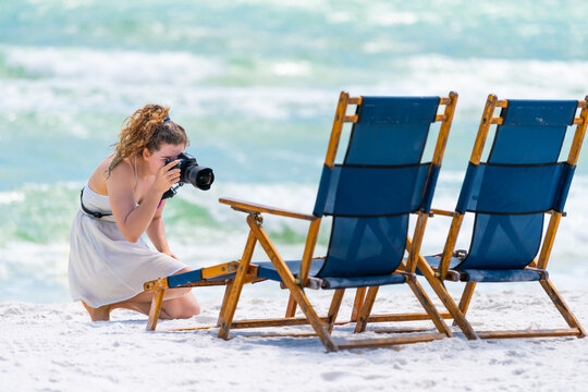 Fort Walton Okaloosa Island Beach in Florida in Gulf of Mexico with young woman photographer taking pictures of lounge chairs by water