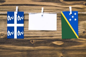Hanging flags of Martinique and Solomon Islands attached to rope with clothes pins with copy space...