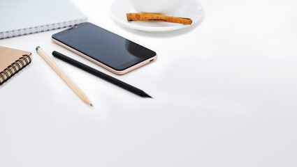Close-up of mobile phone,  notebook, pencil and coffee cup on white desk, Concept using technology from  mobile for business work