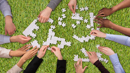 Group Of People Joining The White Puzzles On Grass