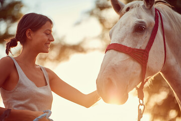 Smiling woman rider and her beautiful horse at summer day on the farm.