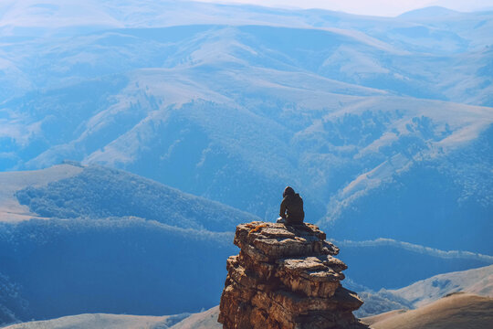 A young man is sitting on a cliff. Caucasian ridge. Mountain landscape. sunny day