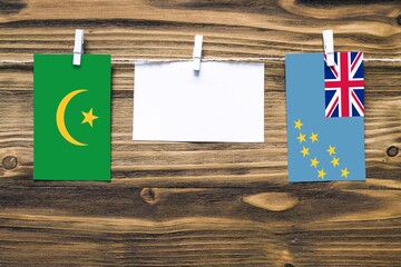 Hanging flags of Mauritania and Tuvalu attached to rope with clothes pins with copy space on white...