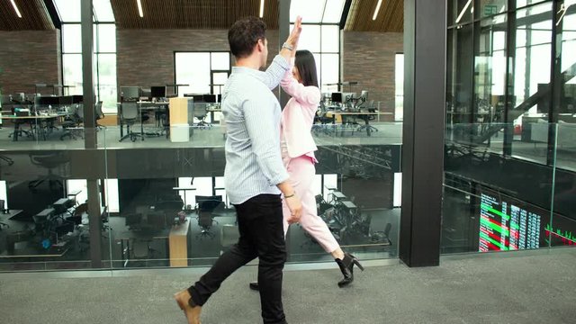 Bullet time shot of smiling business colleagues giving a high 5 as they pass in the office