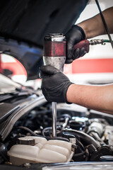Obraz premium Auto mechanic repairer changing spark plugs on the car