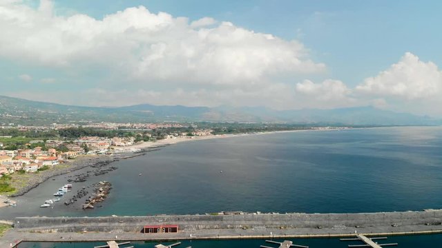 Aerial flyover above marina di riposto port along coast, Sicily Italy