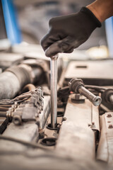 Auto mechanic repairer changing spark plugs on the car