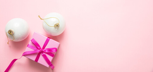 Xmas baubles and gift box against pink background, top view, copy space
